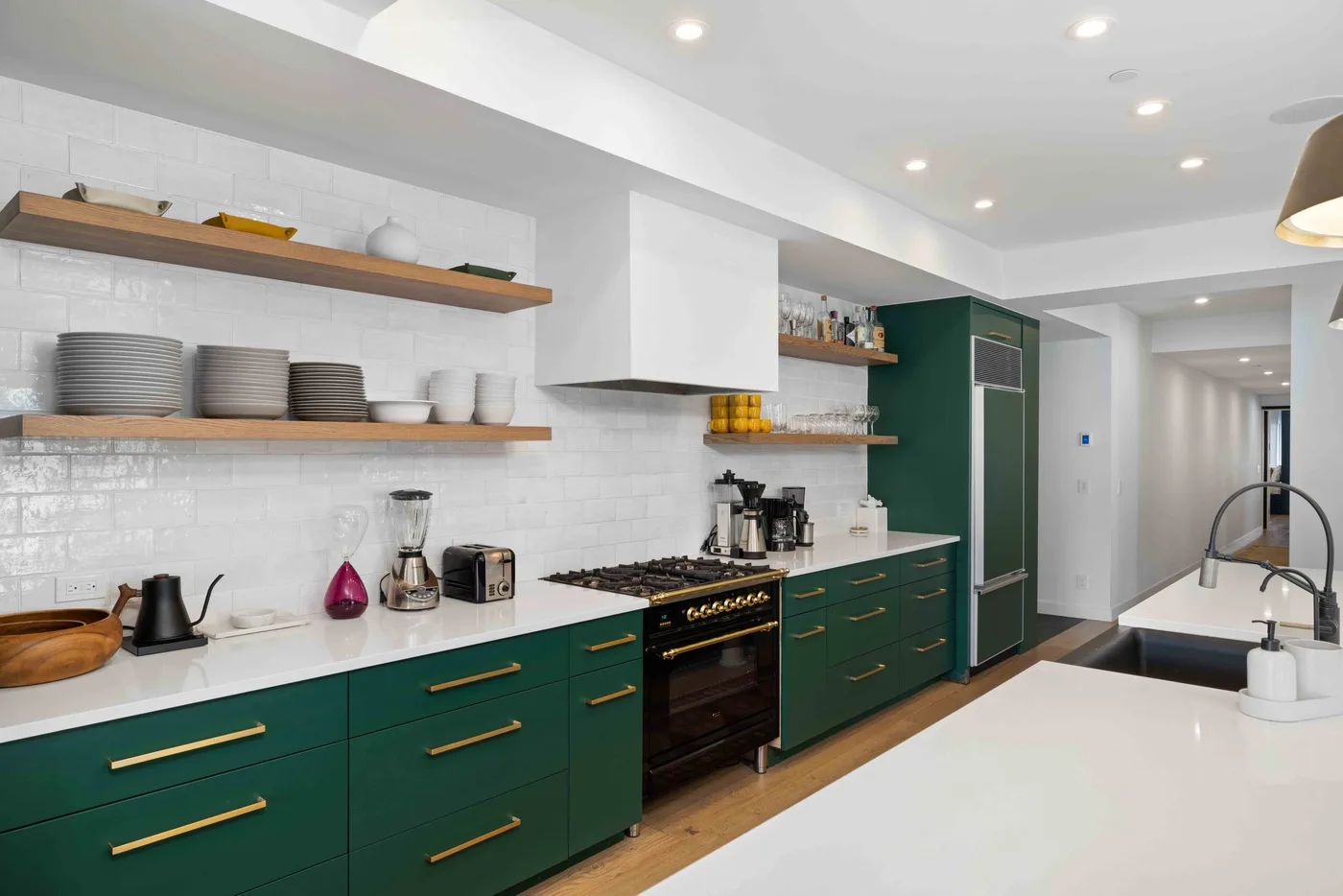Una cocina moderna con gabinetes verdes, estantes abiertos y una isla grande.