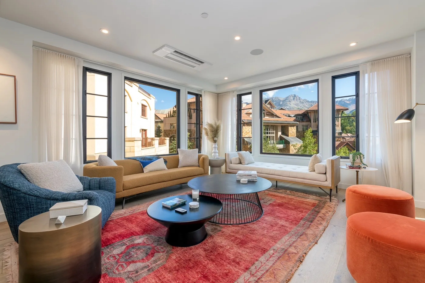 A bright living room has seating around a round coffee table beside large windows.
