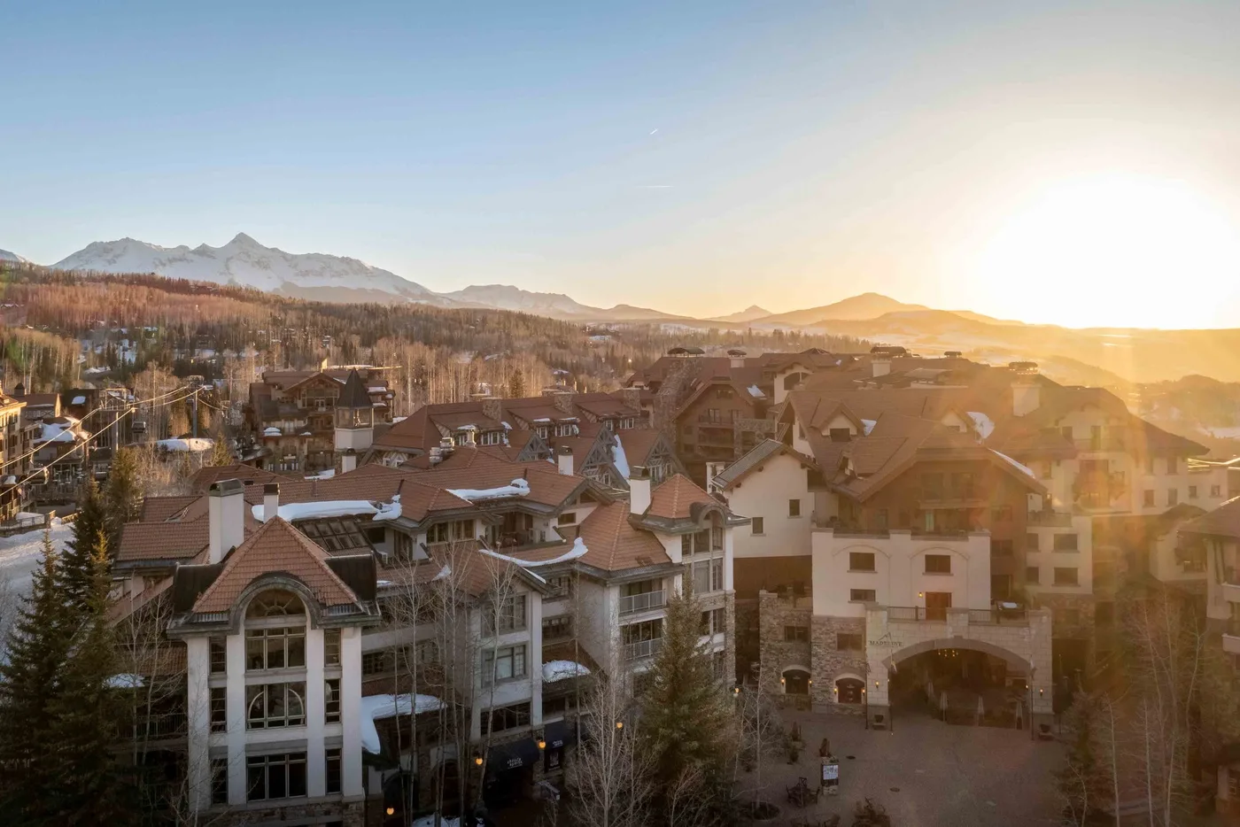 Un pueblo de montaña se extiende por el valle bajo la cálida luz del atardecer.