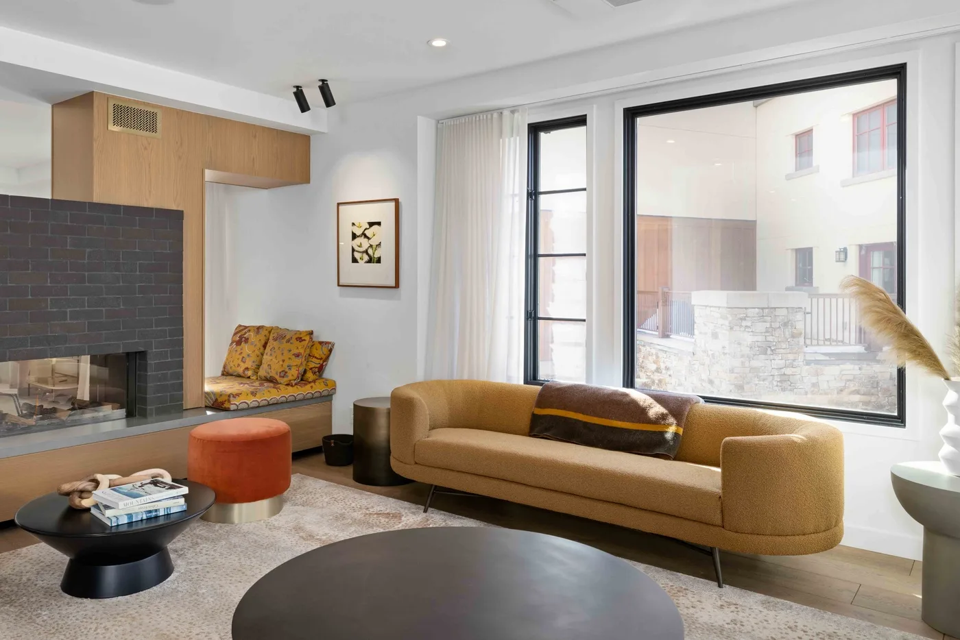 Una sala luminosa con sofá, chimenea y grandes ventanas.