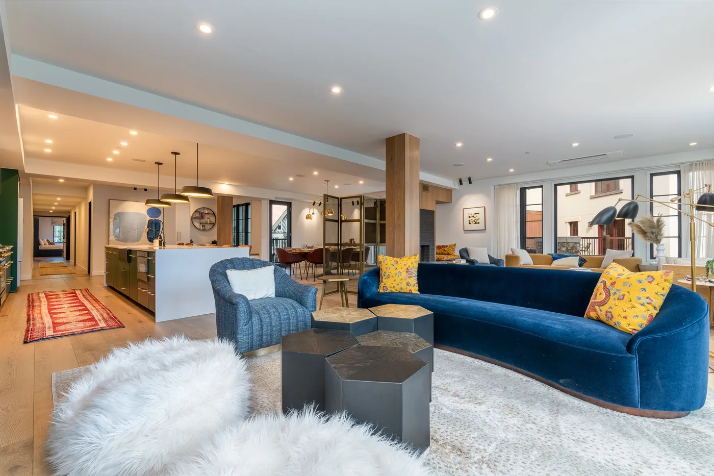 Sala de estar de concepto abierto con asientos azules y una cocina al fondo.