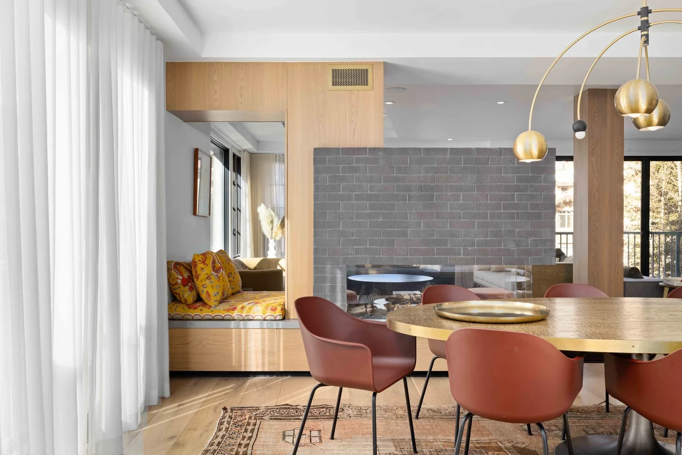 Un comedor con una mesa de madera y lámparas colgantes junto a una pared de ladrillo.