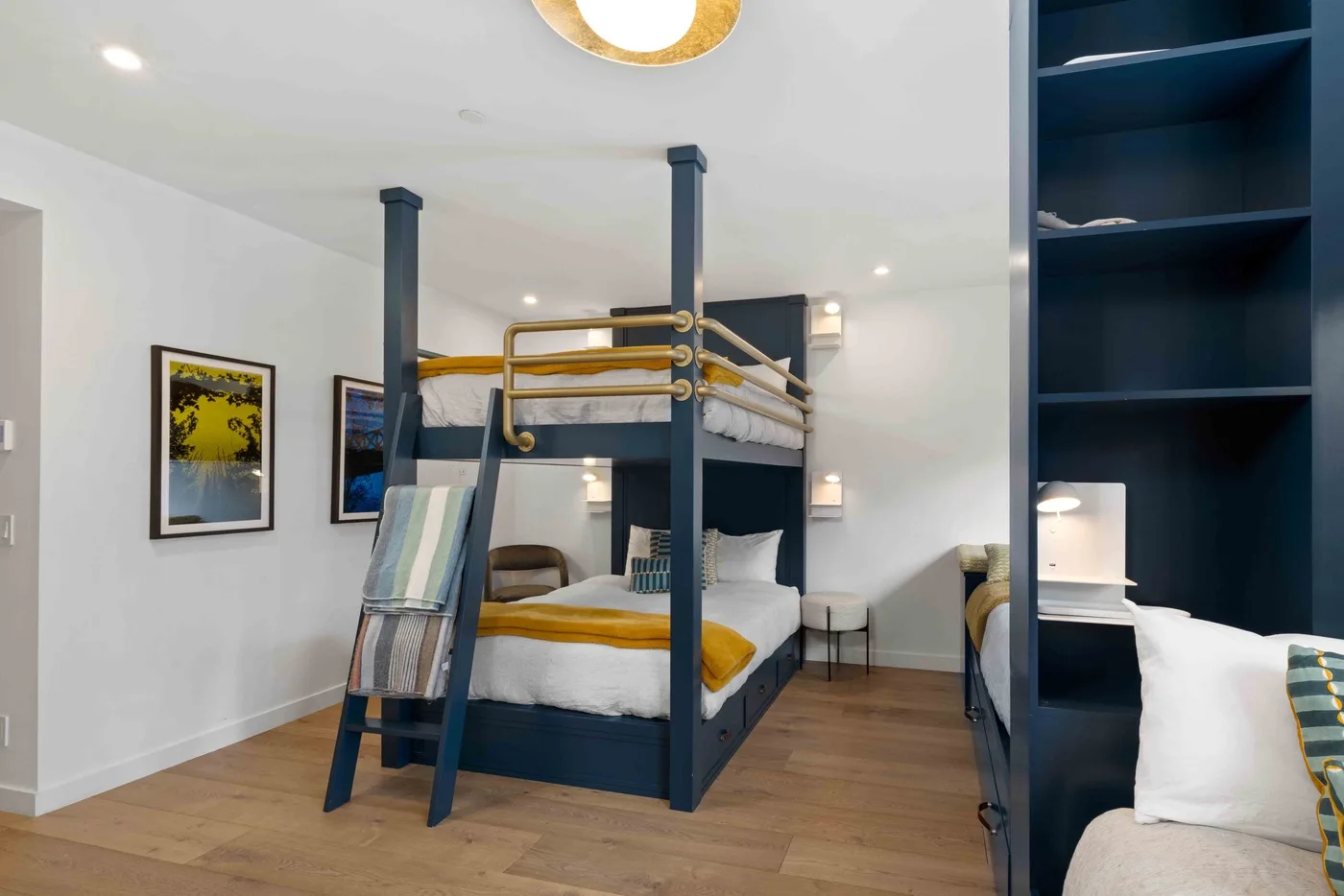 Un dormitorio con literas, ropa de cama blanca y cuadros en la pared.