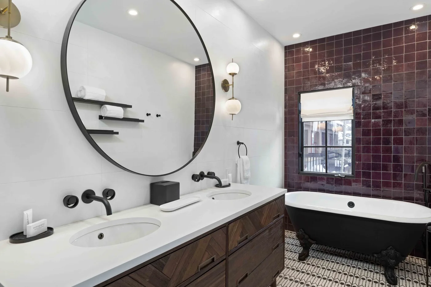Un baño con un tocador largo, un espejo redondo grande y una bañera exenta.