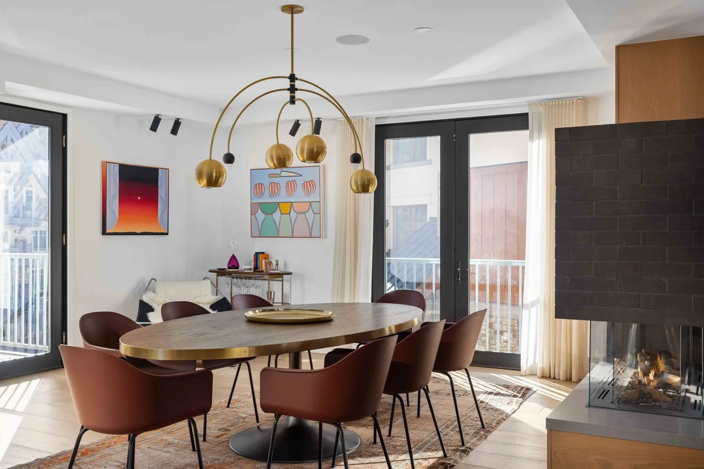 Comedor con una mesa larga y lámparas colgantes junto a grandes ventanas.