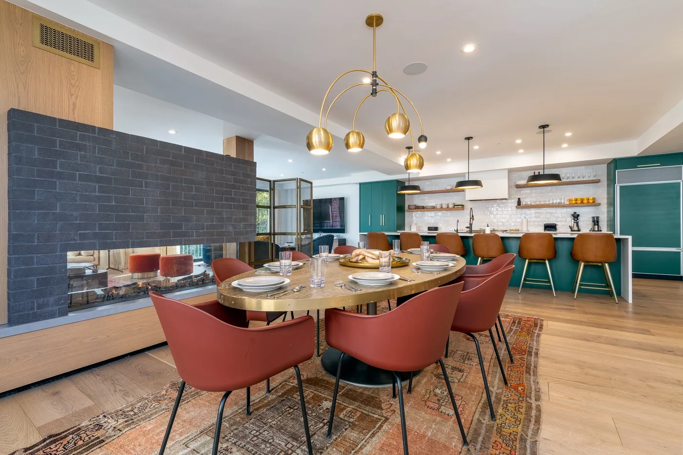 Un comedor con una mesa larga y asientos rojos se abre a la cocina.