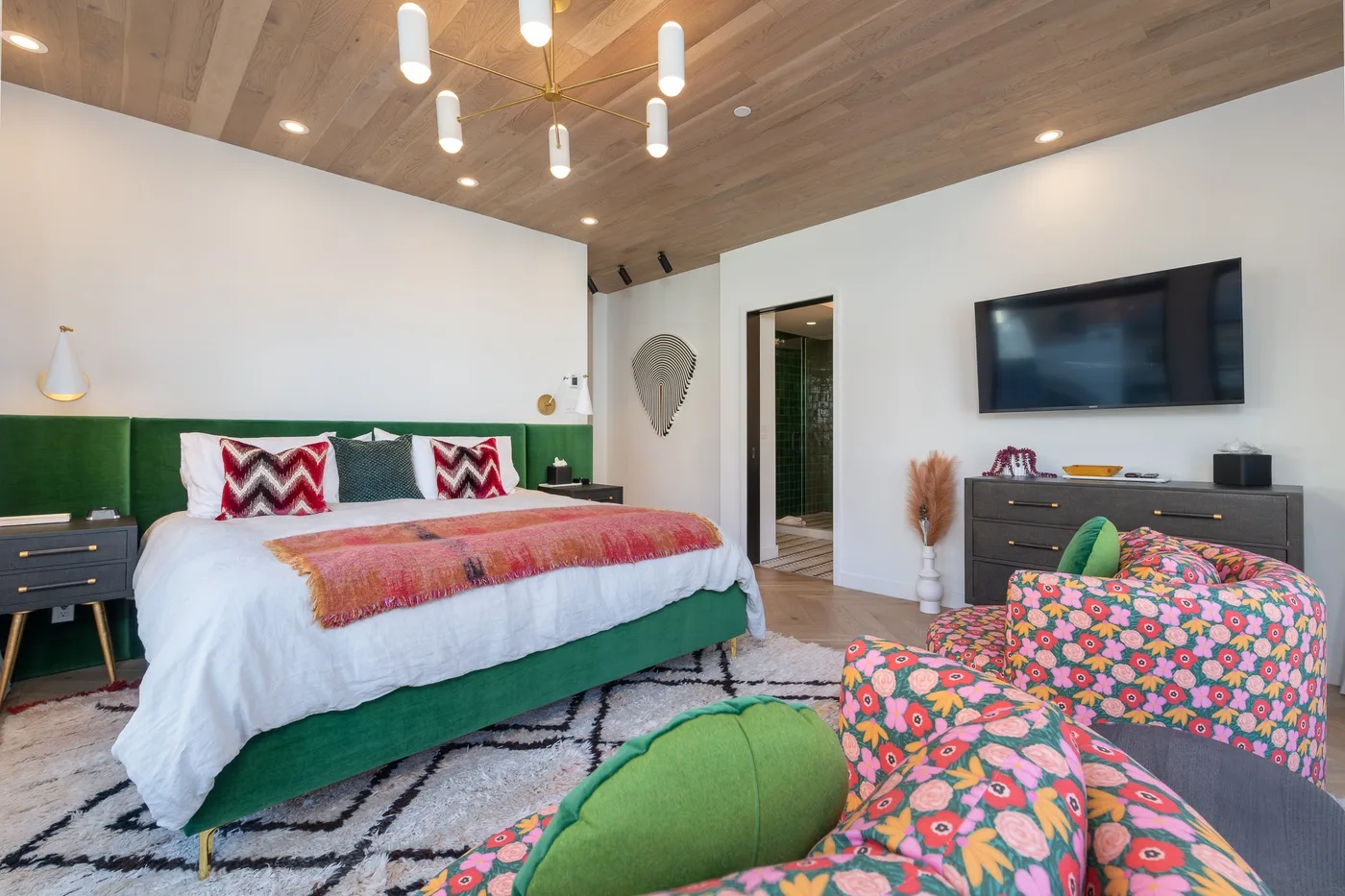 Un dormitorio con una cama grande, ropa de cama estampada y un televisor en la pared.