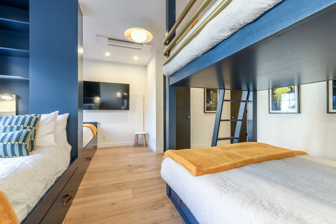 Un dormitorio con literas azules, ropa de cama blanca y un televisor.