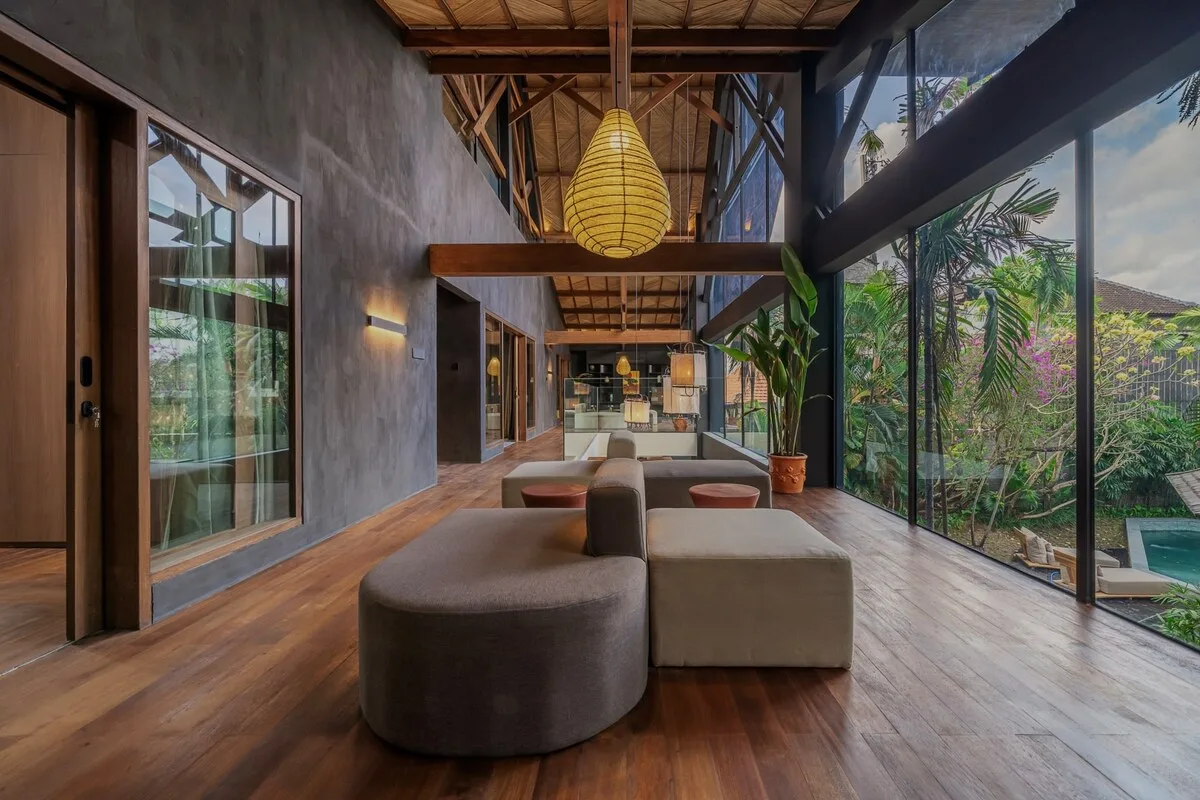 A spacious lounge with seating, a hanging pendant light, and floor-to-ceiling windows.