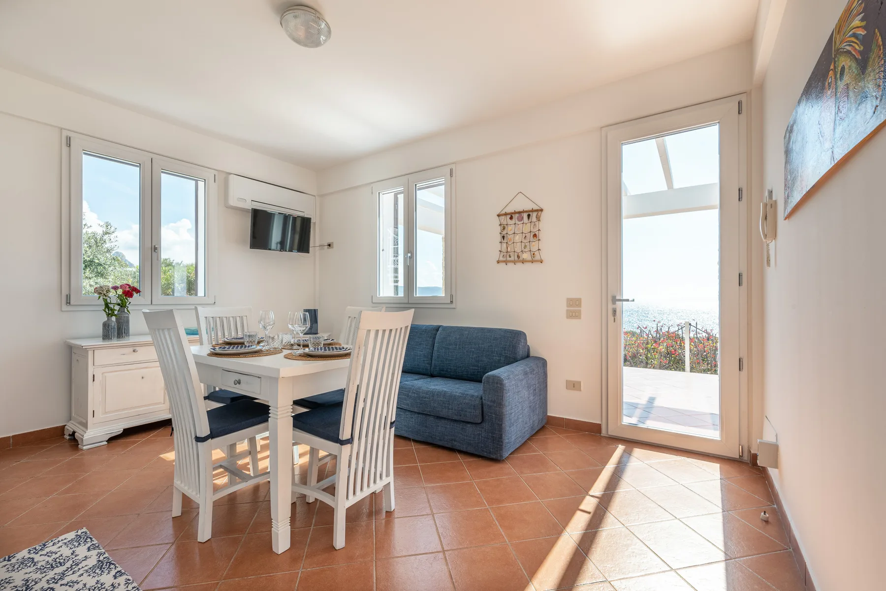 A bright dining and living area with a table, seating, and glass doors.