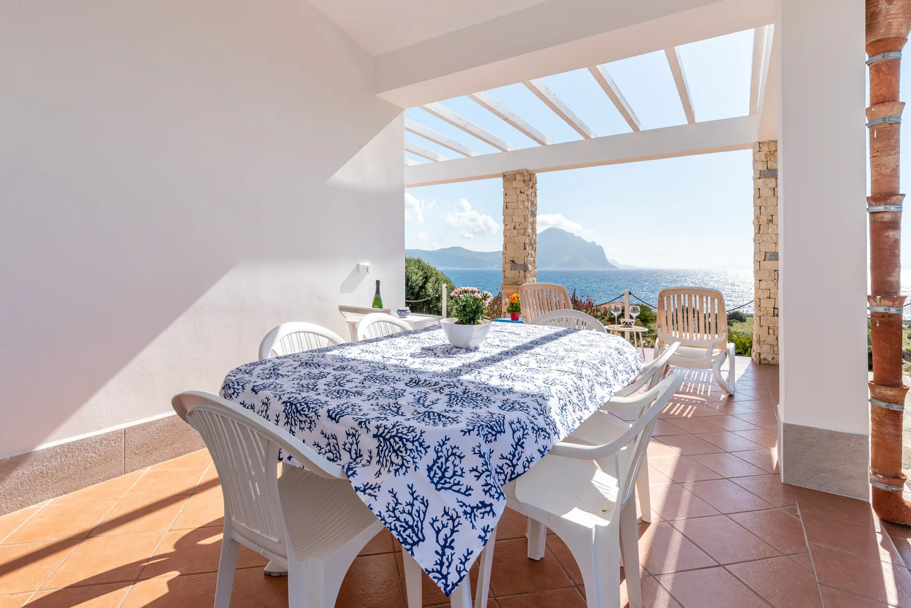 Un comedor con una mesa bajo una pérgola abierta con vistas al mar.