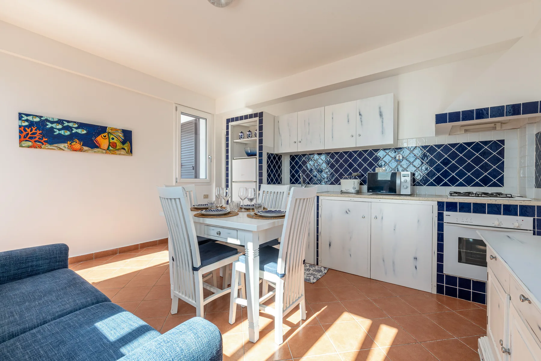 Una cocina y comedor luminosos con gabinetes blancos y una mesa.