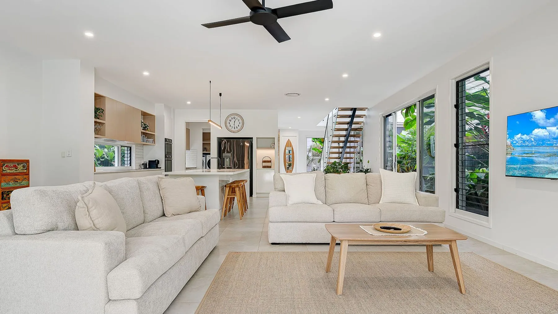A bright living room with seating, a coffee table, and large windows.