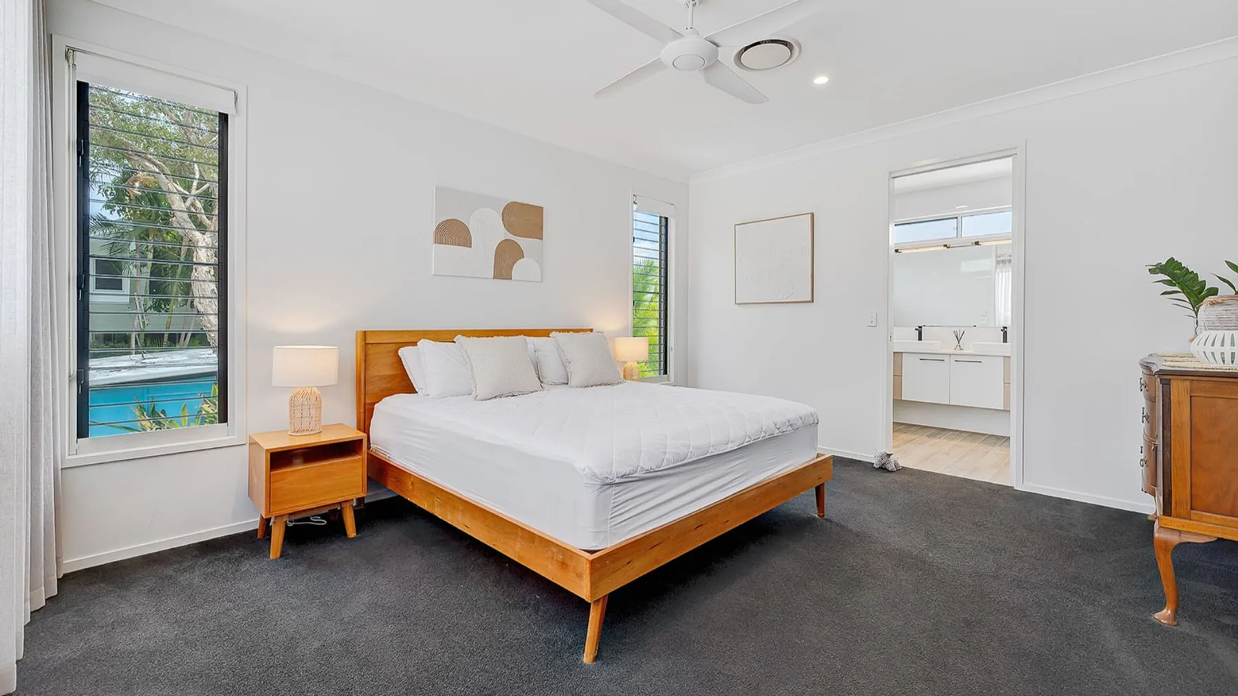 A bright bedroom with a wooden bed and an open doorway to a bathroom.