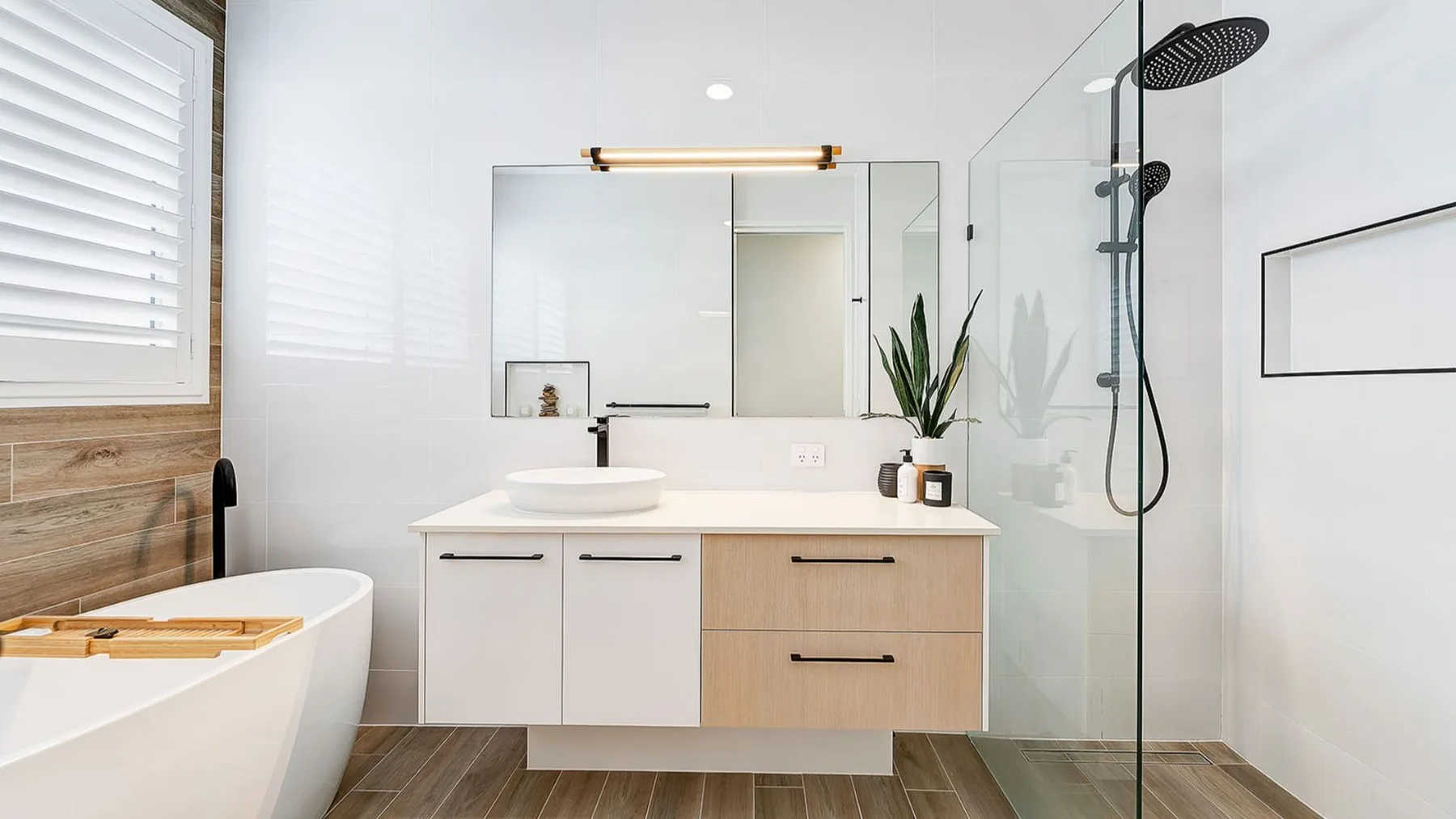A bright bathroom with a bathtub, vanity, and glass shower.