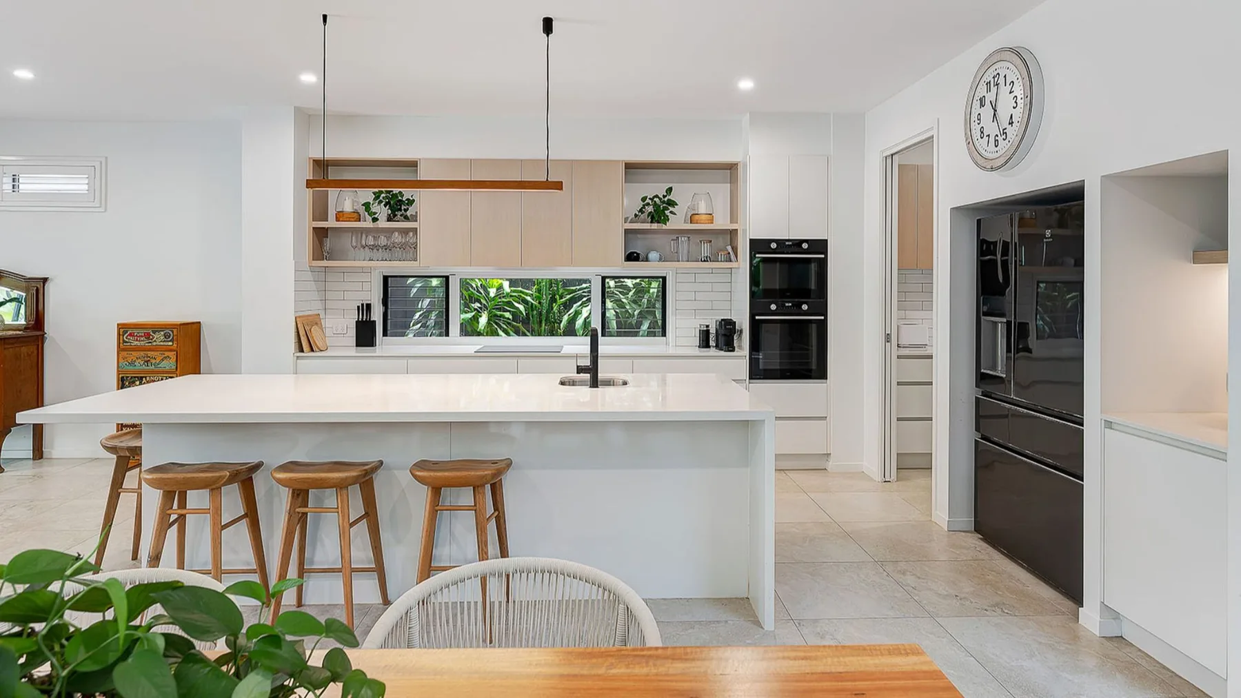 Bright kitchen with a long island, wooden stools, and built-in appliances.