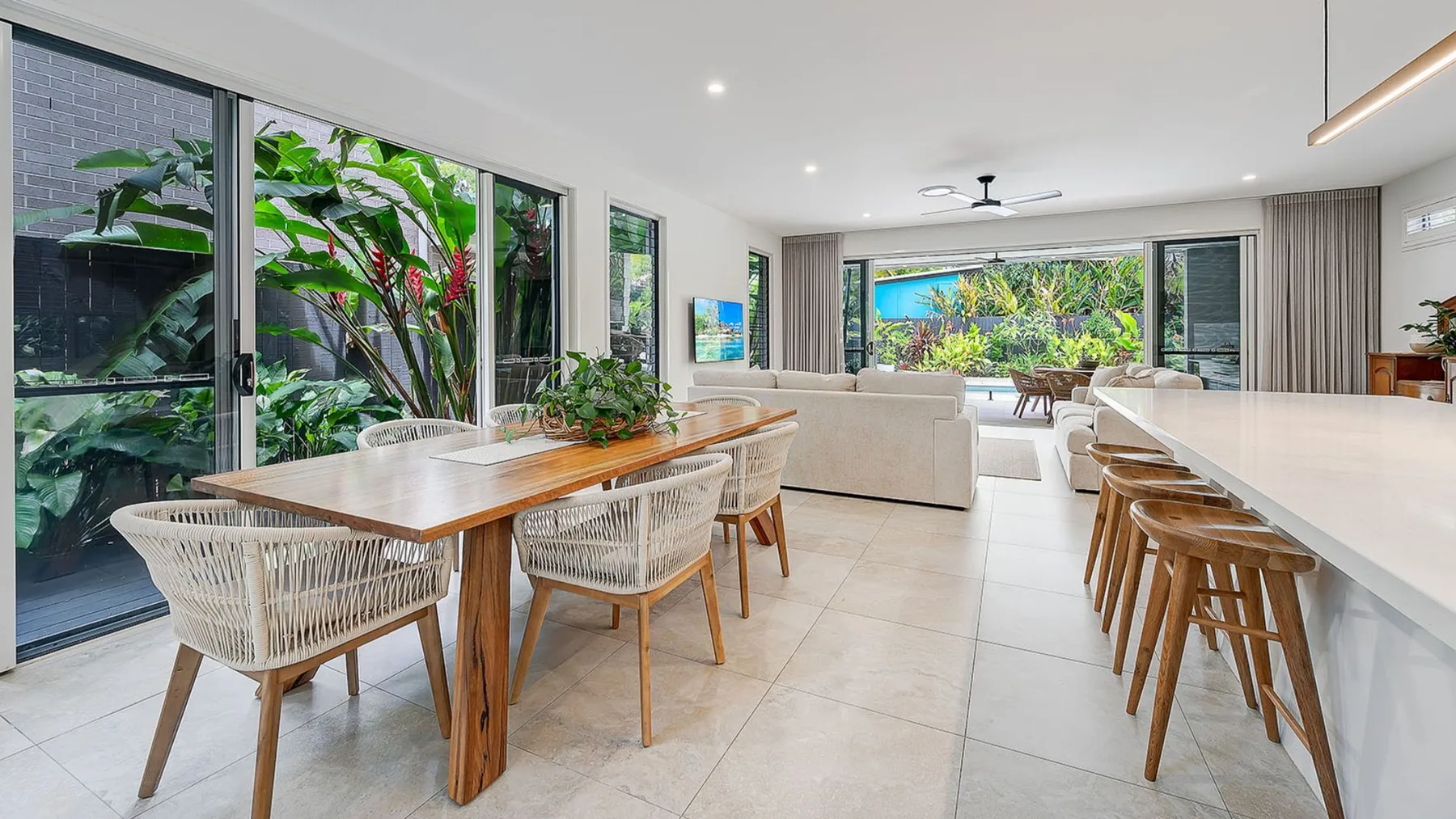 An open-plan dining and living area opens onto a garden through large glass doors.