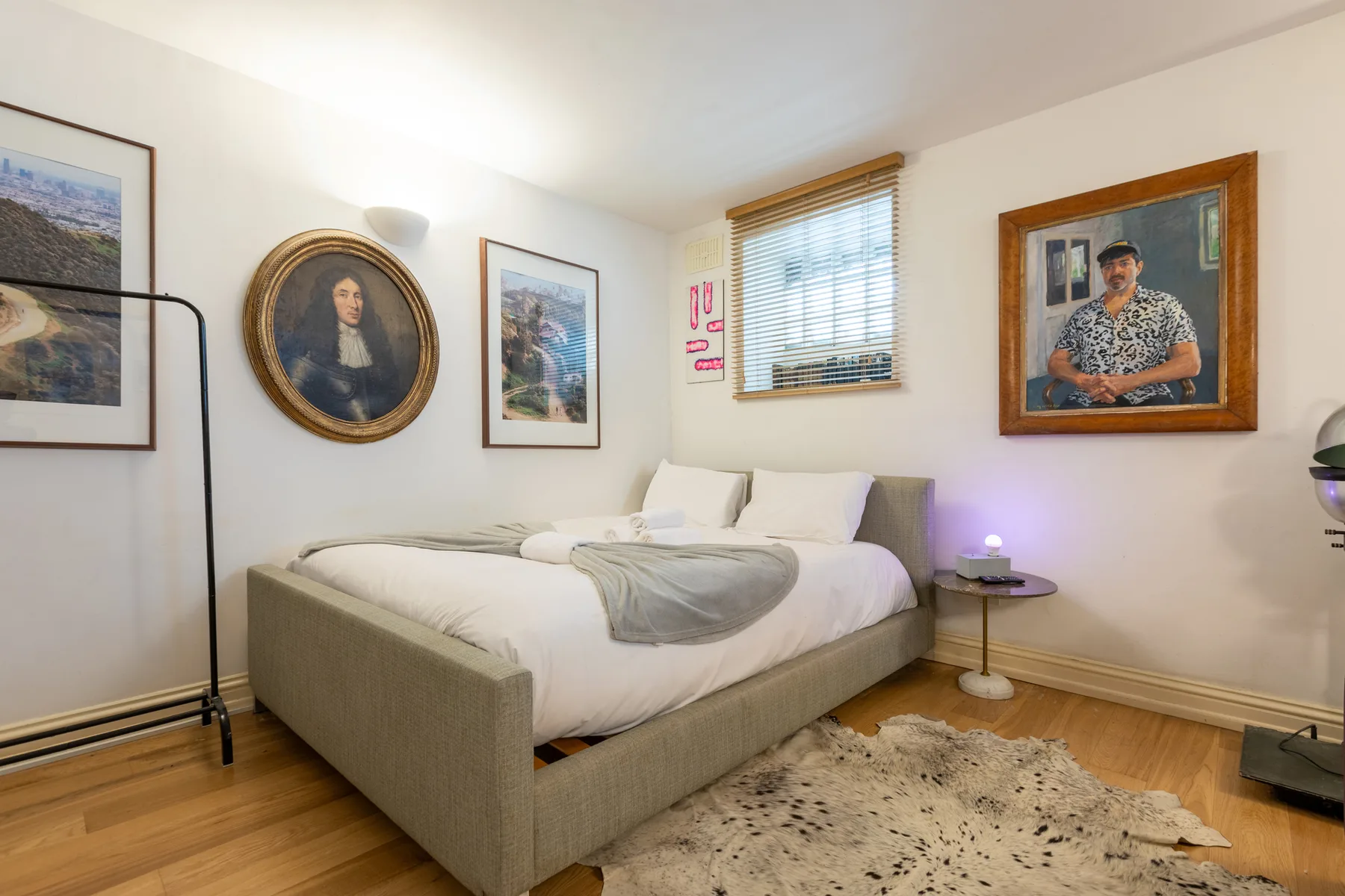 Dormitorio con una cama, cuadros enmarcados y una ventana con persianas.