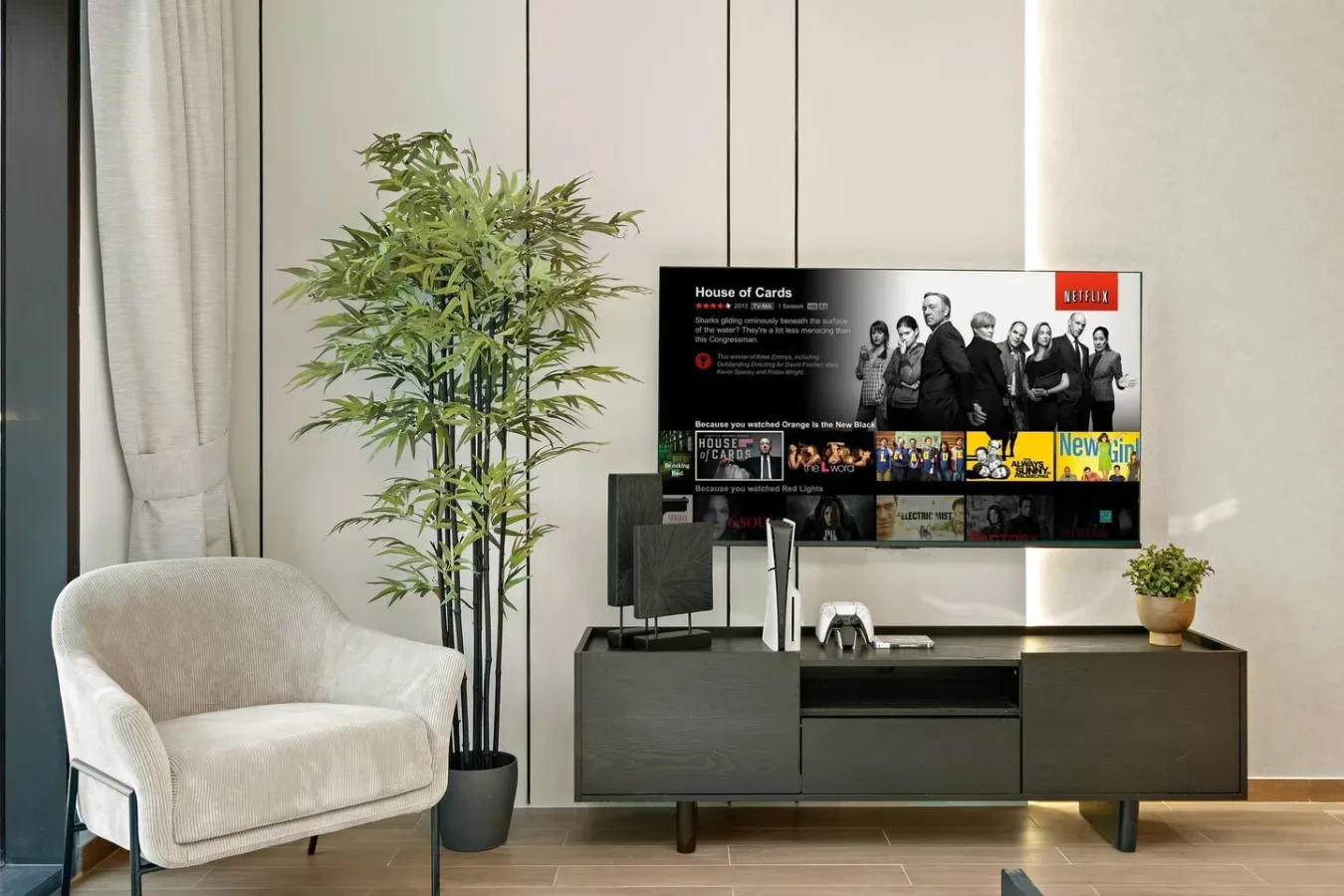 Una sala de estar con un televisor sobre un mueble bajo junto a un sillón claro.
