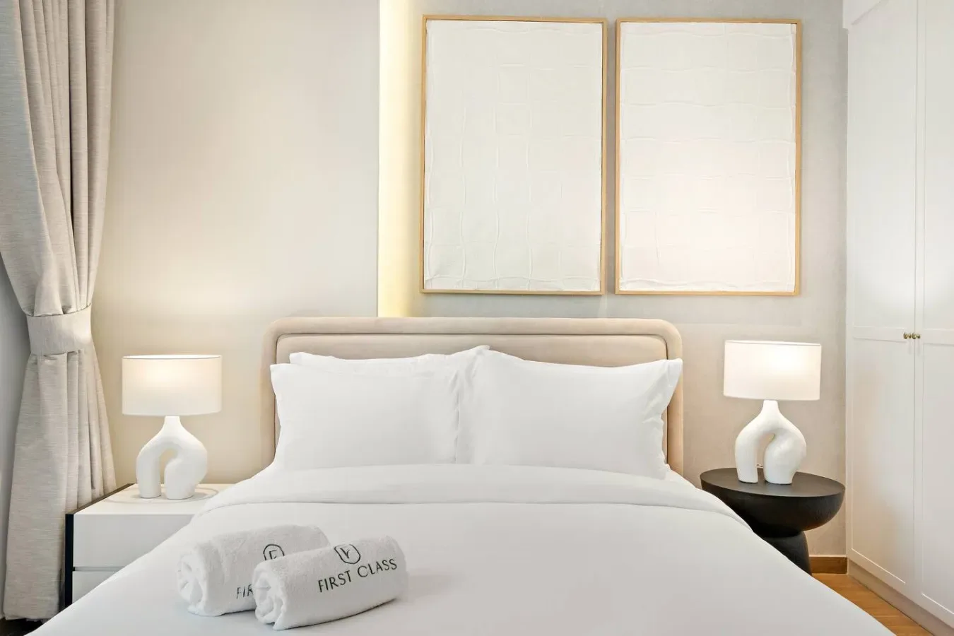 Un dormitorio con una cama bien hecha y cuadros enmarcados sobre el cabecero.
