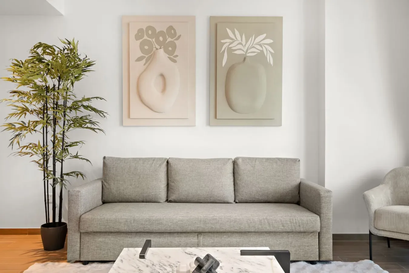 Una sala de estar con un sofá gris bajo dos láminas botánicas enmarcadas.