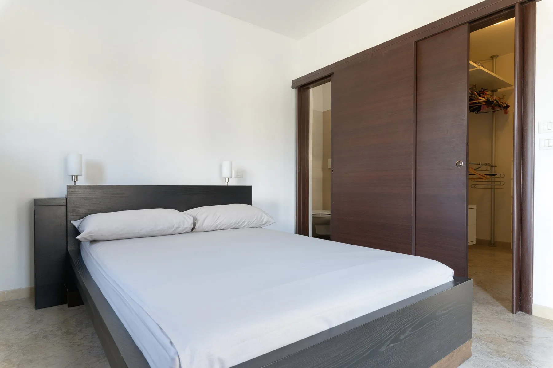 Un dormitorio con una cama bien tendida y un armario abierto.