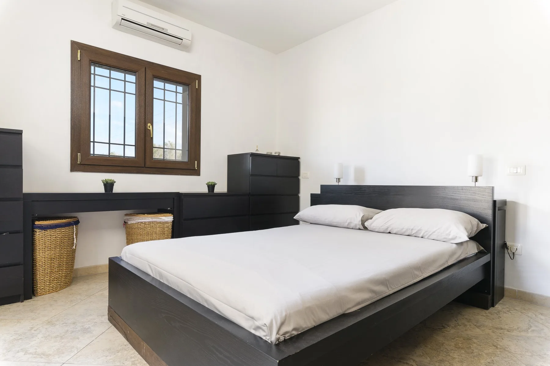 Un dormitorio con una cama, muebles oscuros y una ventana.