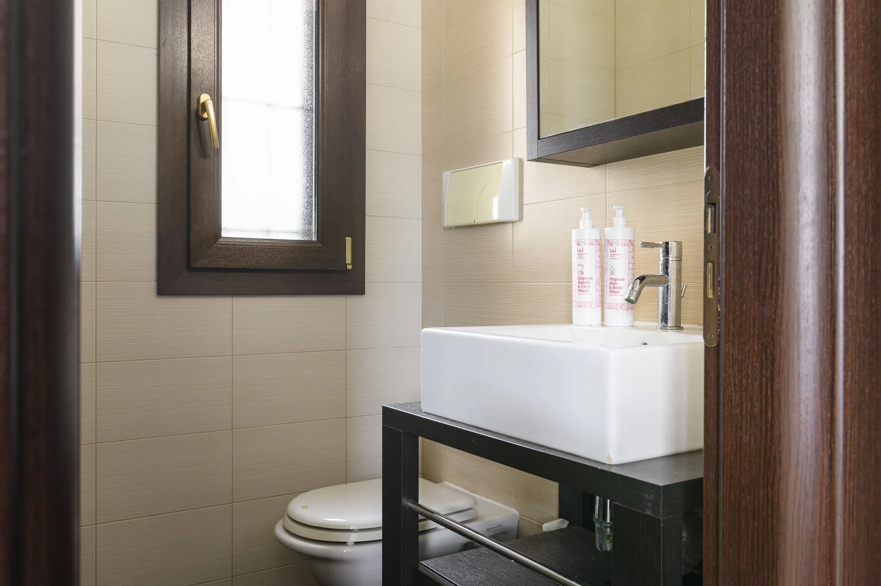 Un baño con azulejos, lavabo, espejo e inodoro.