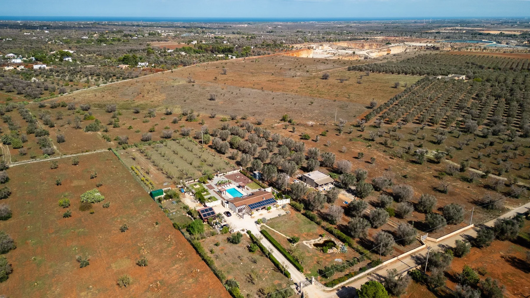 Una vista aérea muestra una propiedad rodeada de campos secos y árboles dispersos.