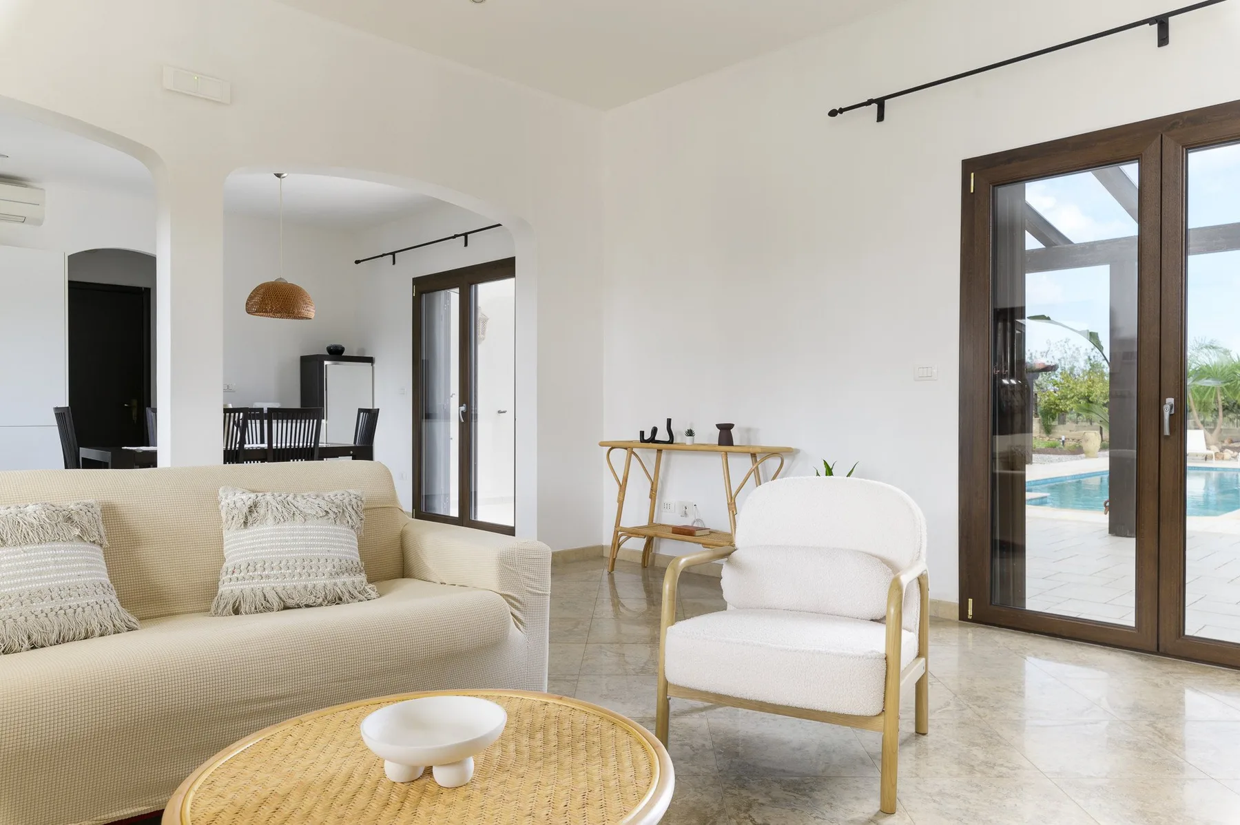 Una sala luminosa con asientos claros y grandes puertas de vidrio que dan a un patio.