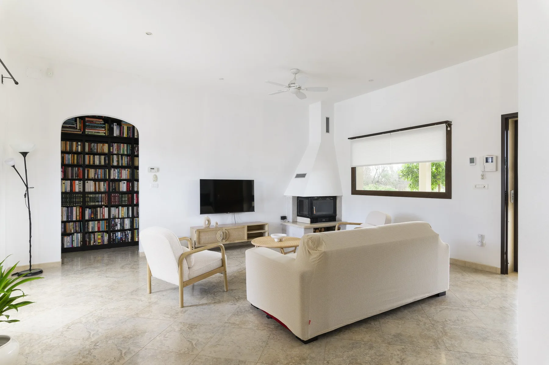 Una sala luminosa con asientos dispuestos alrededor de un televisor y una chimenea.