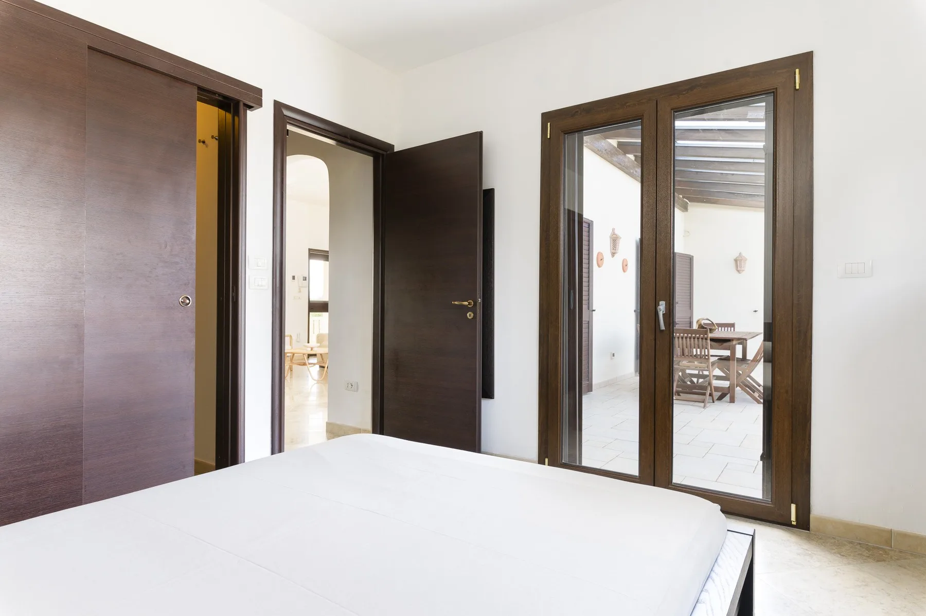 Un dormitorio con una cama en primer plano y puertas de madera oscura.
