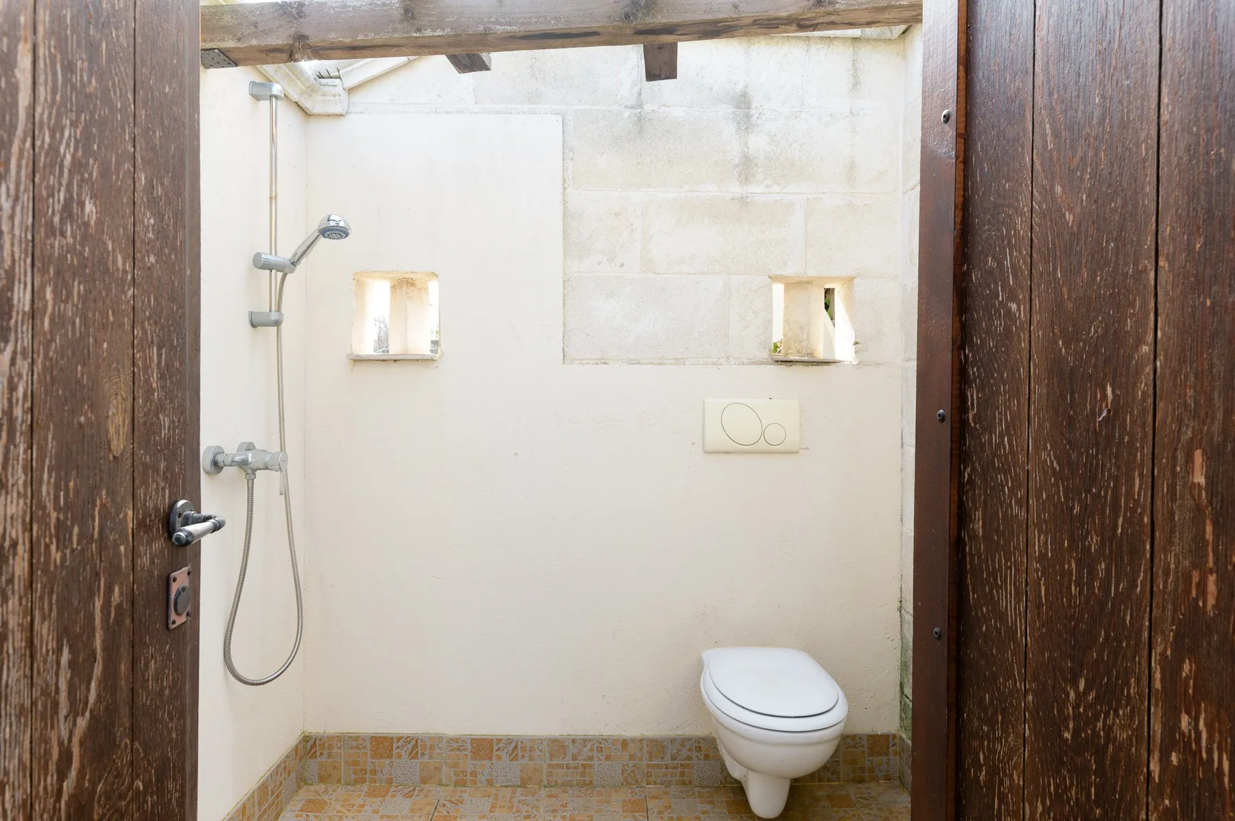 Un baño con ducha, inodoro y pequeños nichos en la pared.