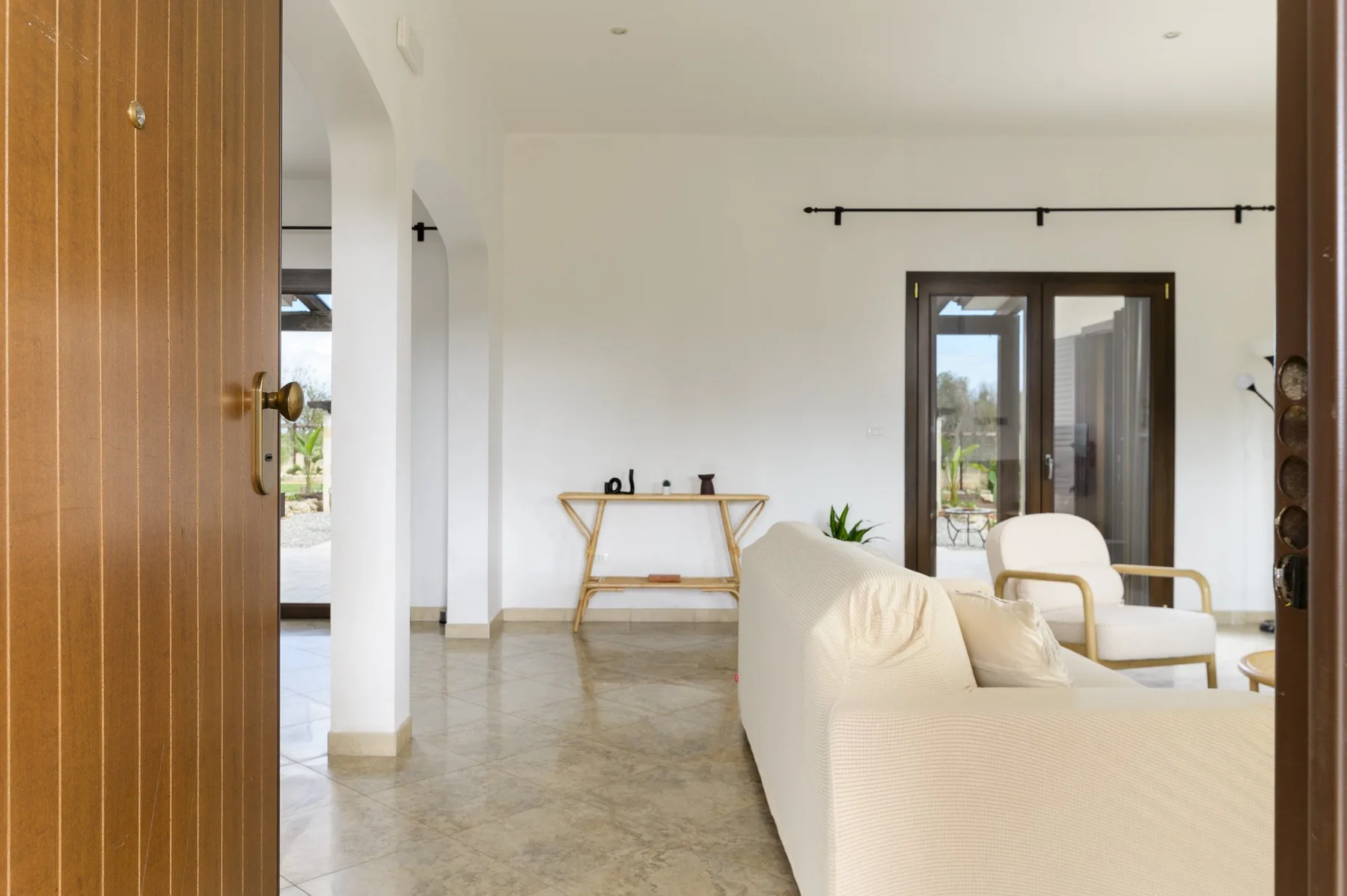 Una sala luminosa con asientos, una consola y puertas de vidrio.