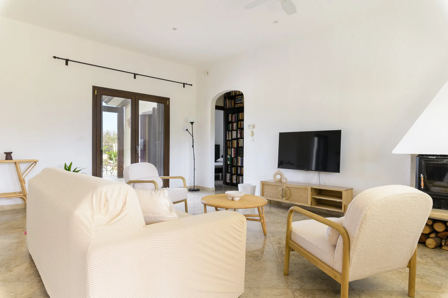 Una sala luminosa con asientos claros, un televisor y una mesa de centro.