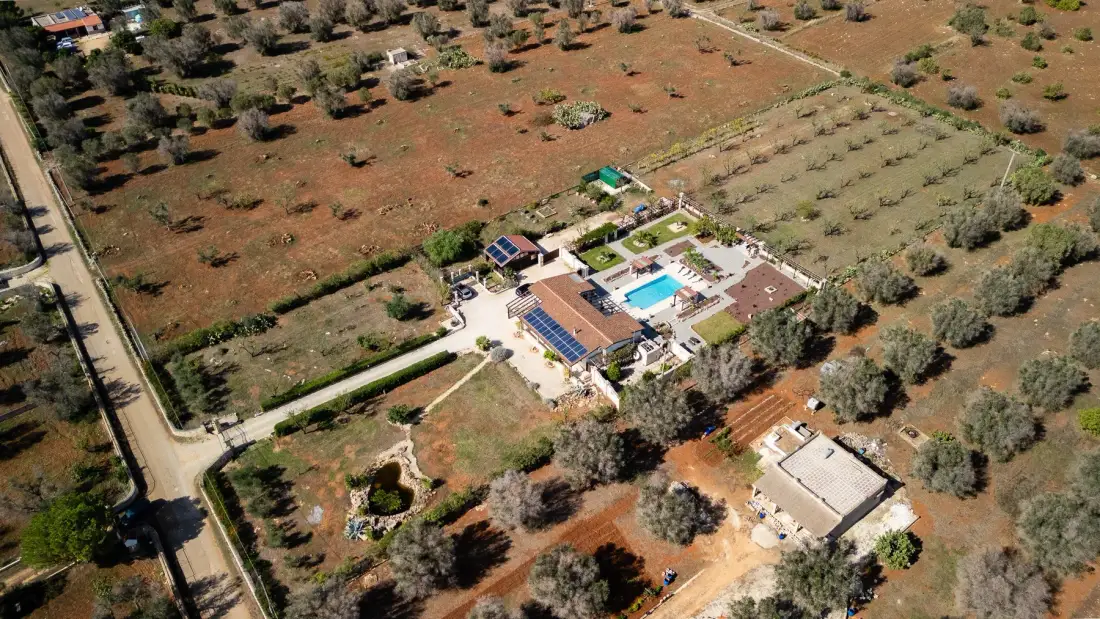 Vista aérea de una propiedad rural con piscina y campos alrededor.