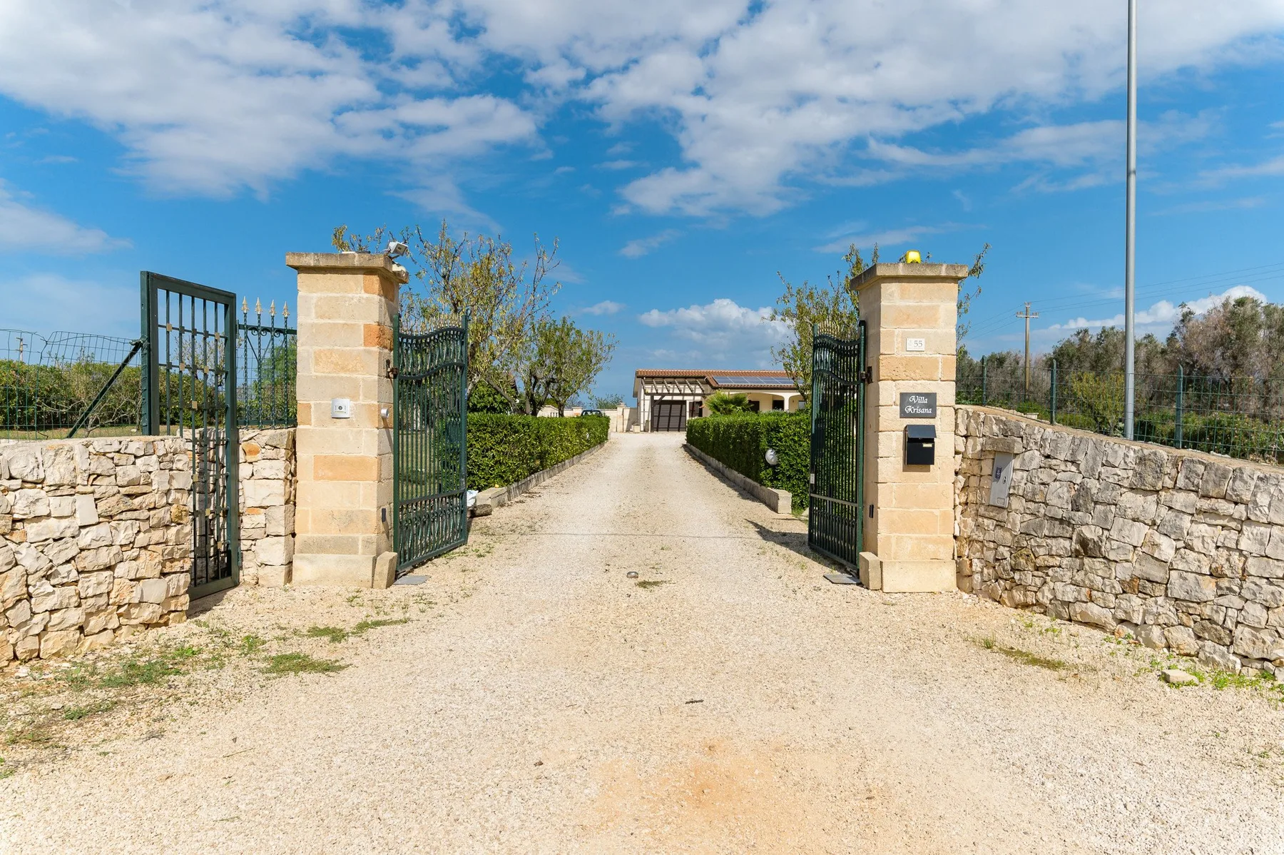 Un camino de grava atraviesa una puerta abierta entre muros de piedra.