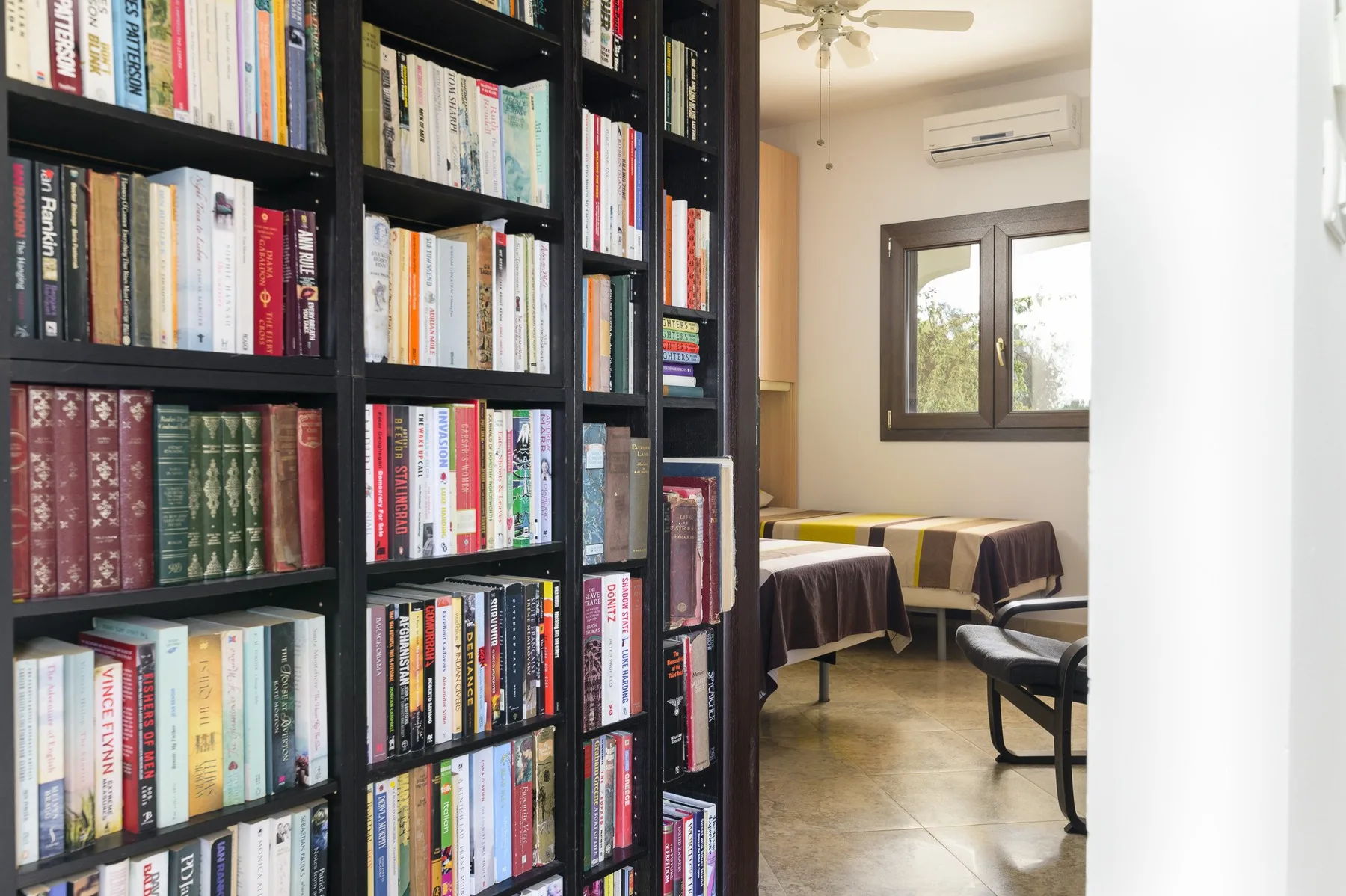 Una habitación con estanterías altas junto a una mesa y sillas.