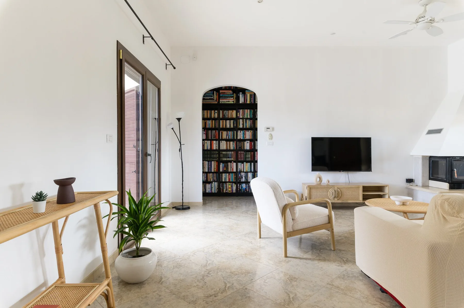 Una sala de estar luminosa con asientos, un televisor y una estantería.