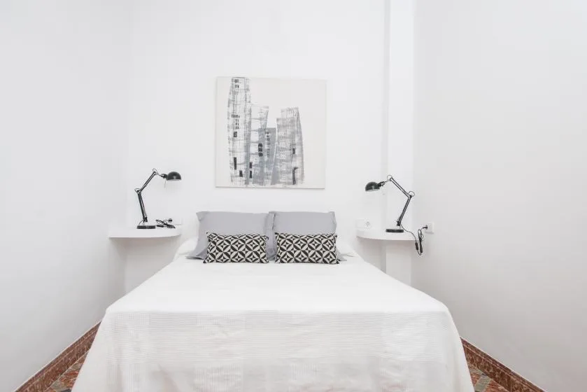 Un dormitorio luminoso con una cama bien arreglada y lámparas de noche a juego.