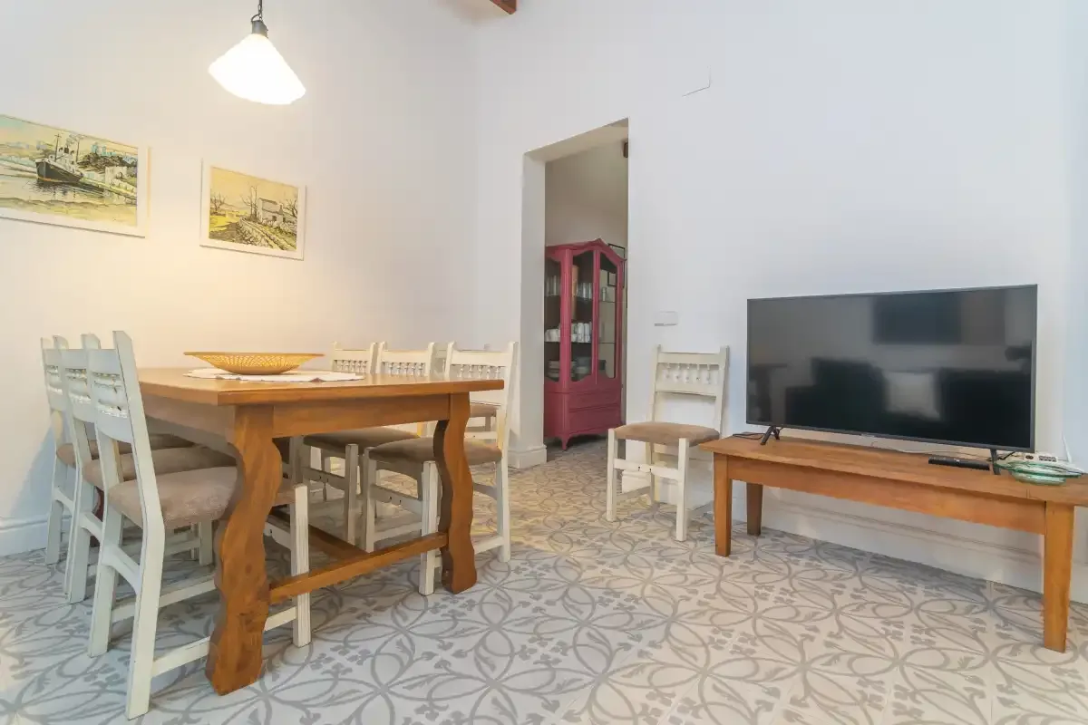 Comedor con una mesa de madera y sillas junto a un televisor.