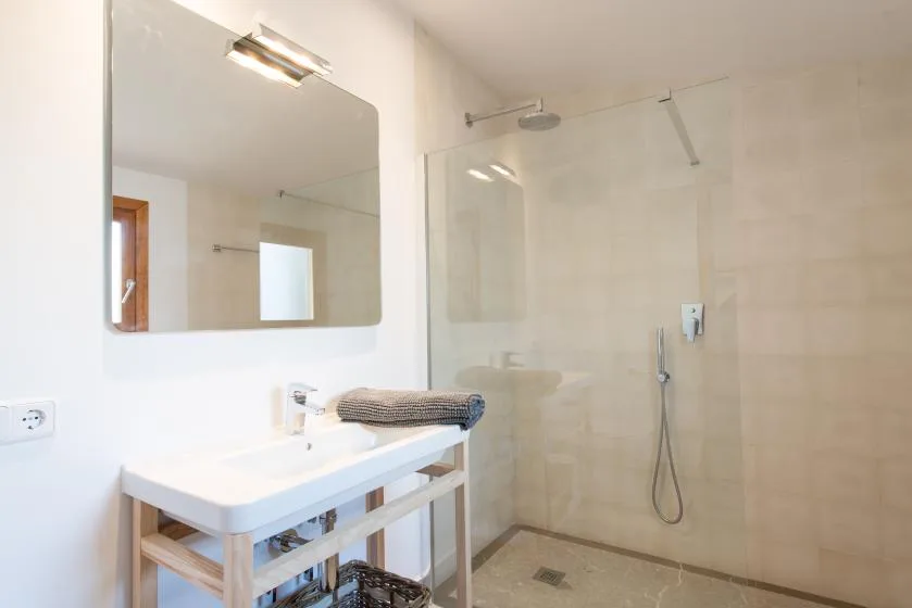 Un baño luminoso con un lavabo y una ducha con mampara de vidrio.