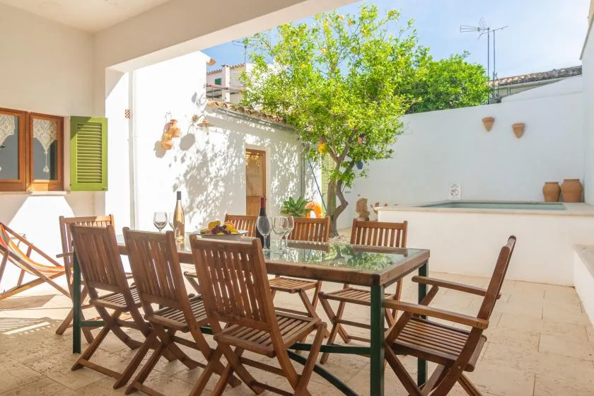 Comedor al aire libre con una mesa de madera y asientos bajo un árbol frondoso.