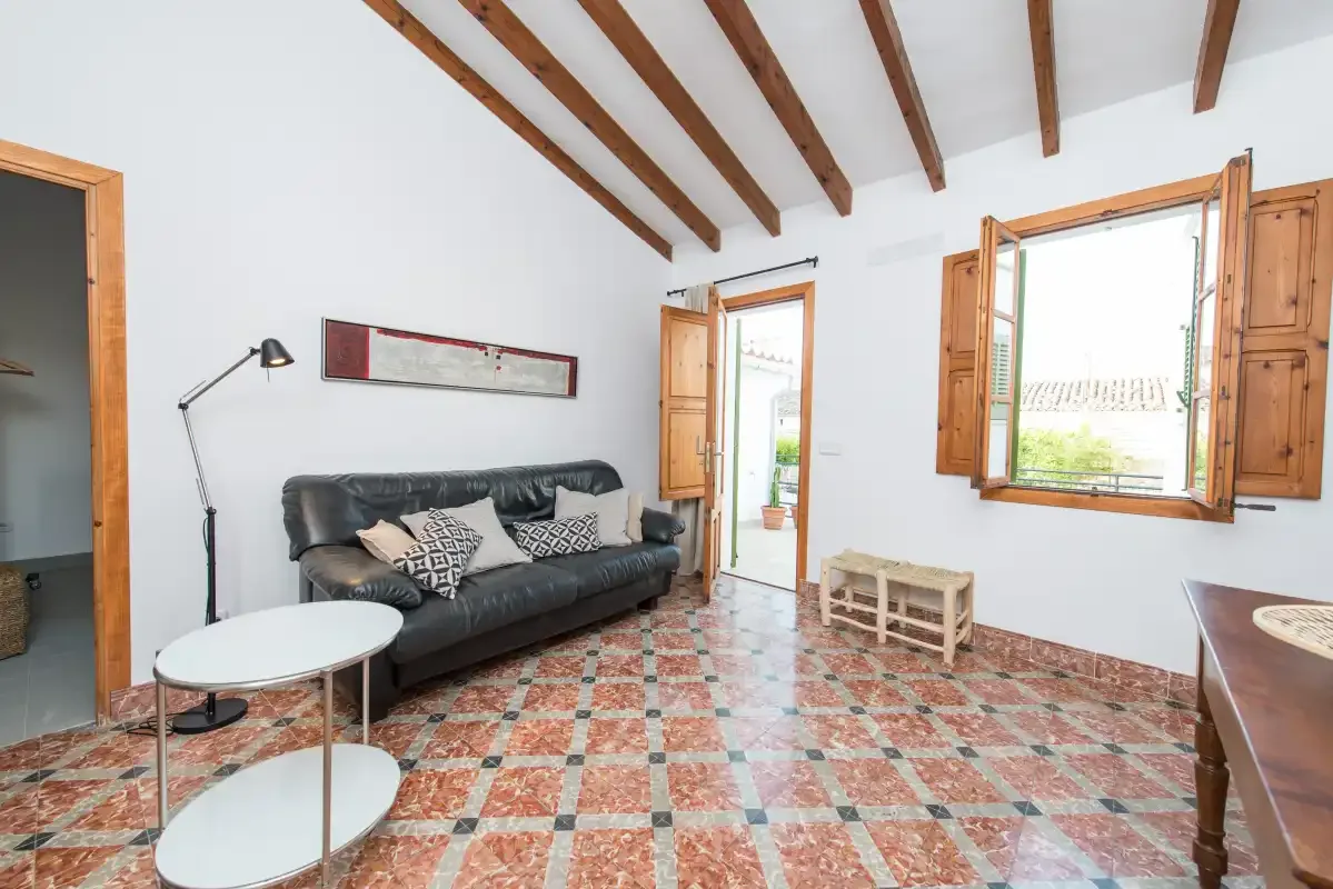 Una luminosa sala de estar con asientos, vigas de madera a la vista y ventanas abiertas.
