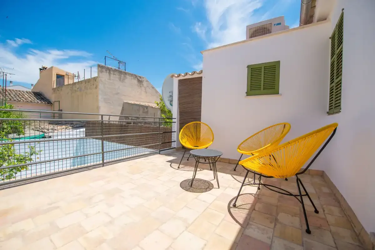 Una terraza soleada con asientos amarillos y una barandilla metálica.