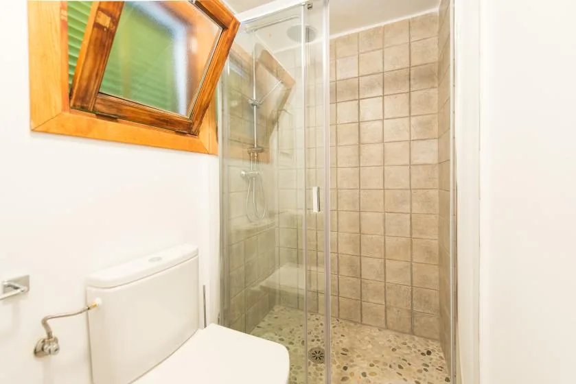 Un baño con ducha de vidrio, paredes de azulejos y una ventana.