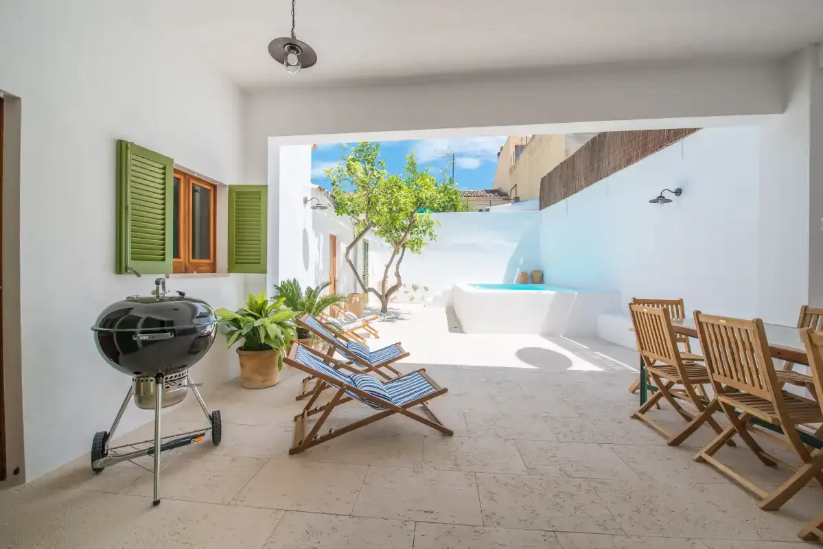 Un patio luminoso con asientos, una mesa de comedor y una barbacoa.