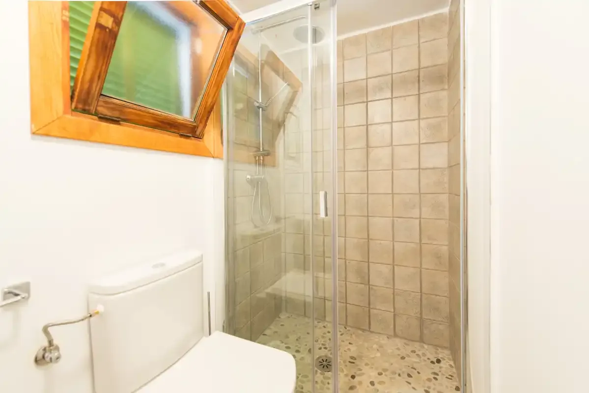 Un baño con inodoro y ducha alicatada.