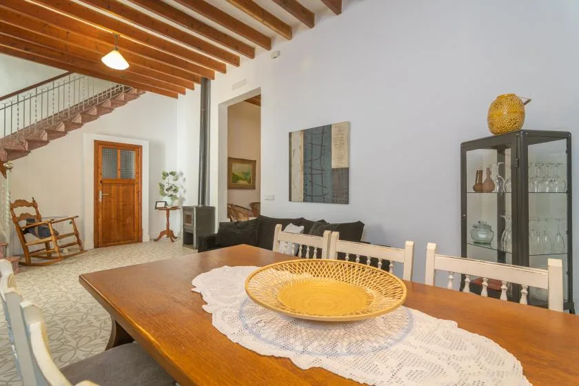 Comedor con una mesa de madera bajo vigas de techo expuestas.