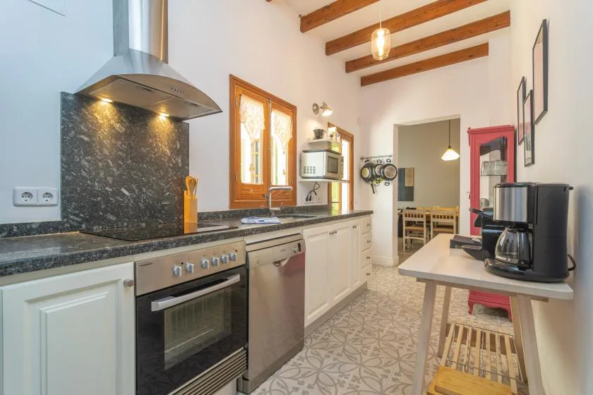 Una cocina luminosa con una encimera larga y vigas de madera vistas.